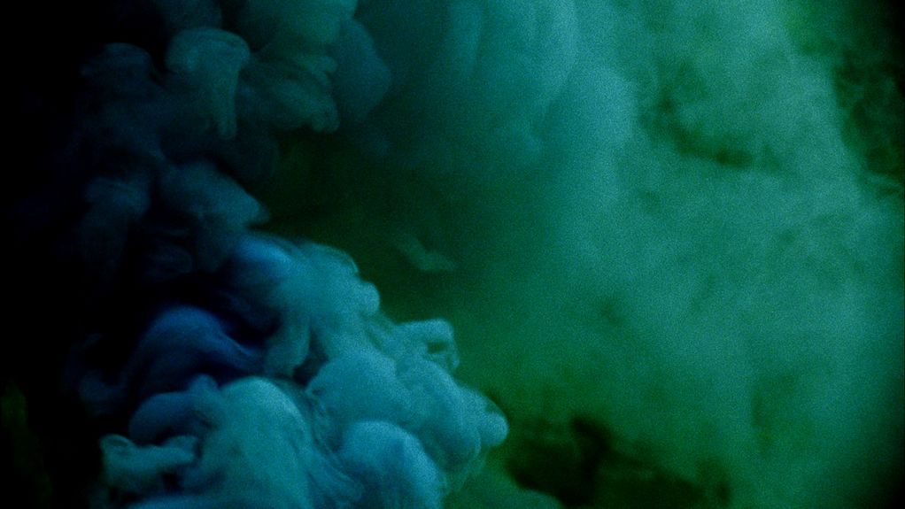 Auf diesem Filmstill sieht man Rauchwolken in den Farbtönen dunkelblau bis türkis.