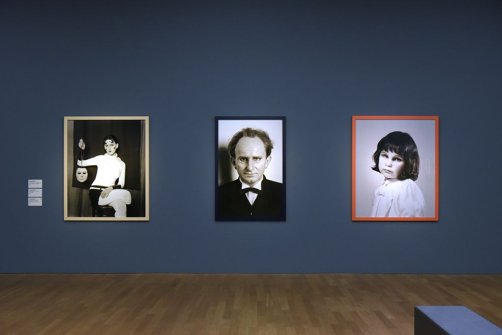 Three photographs in an exhibition room